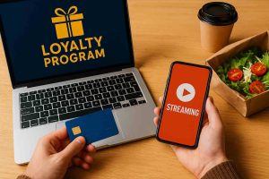 A realistic photo of a loyalty program integrated with streaming and delivery services, featuring a laptop, smartphone, and a blue loyalty card on a wooden table.